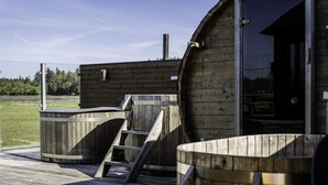 Une cabane en bois dotée d’une terrasse, d’un jacuzzi et d’une échelle menant à une porte.