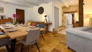 Un coin repas avec une table en bois dressée pour quatre personnes, un canapé et un mur en pierre.