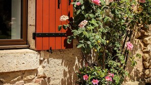 Un mur de pierre avec une fenêtre ornée de volets rouges.