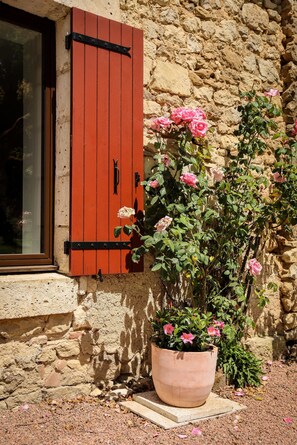 Eine Mauer aus Stein mit einem Fenster und roten Fensterläden.