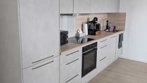 A modern kitchen with grey cabinets, a built-in oven, and a coffee machine. - Small cozy vacation apartment on the 1OG (Werther (Westfalen))