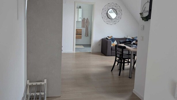 A modern interior with a dining area, a sofa, and a kitchen visible through an open door. - Small cozy vacation apartment on the 1OG (Werther (Westfalen))