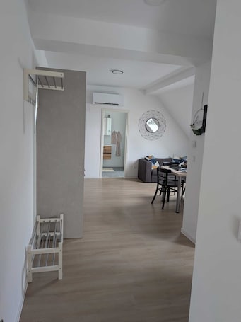 A modern interior with a dining area, a sofa, and a kitchen visible through an open door.. Small cozy vacation apartment on the 1OG