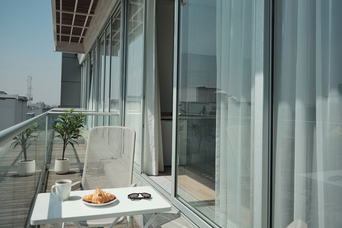 Ein Balkon mit Tisch, Stuhl, einer Speisenplatte, einer Tasse und einer Sonnenbrille.