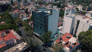A high-rise building with a modern glass facade, surrounded by other buildings and trees. - Roma Residence Luxury Suites  (Ciudad de México)