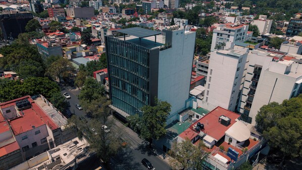 A high-rise building with a modern glass facade, surrounded by other buildings and trees. - Roma Residence Luxury Suites  (Ciudad de México)