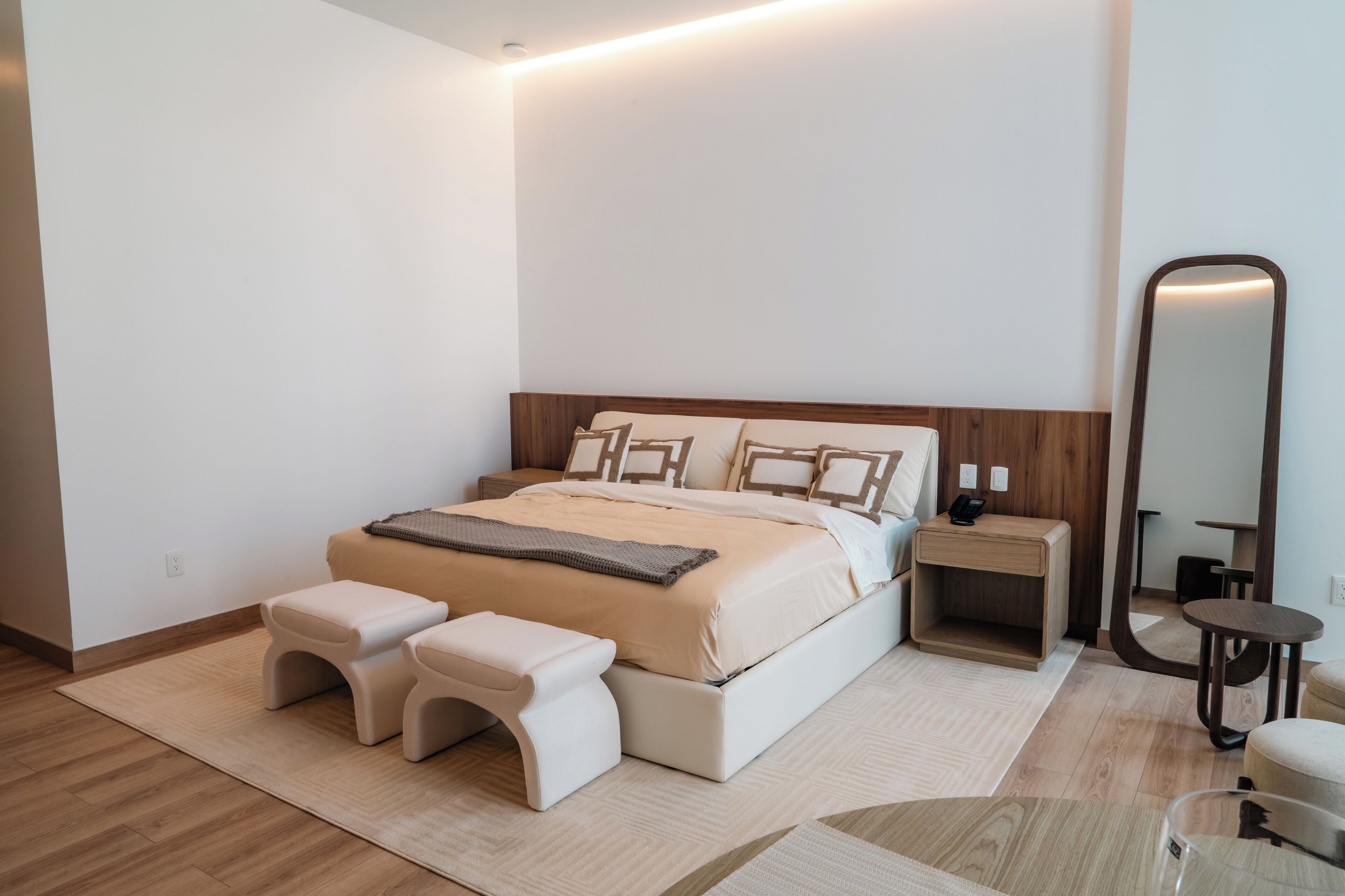 A bedroom with a bed, two bedside tables, a nightstand, a mirror, and a small round table.