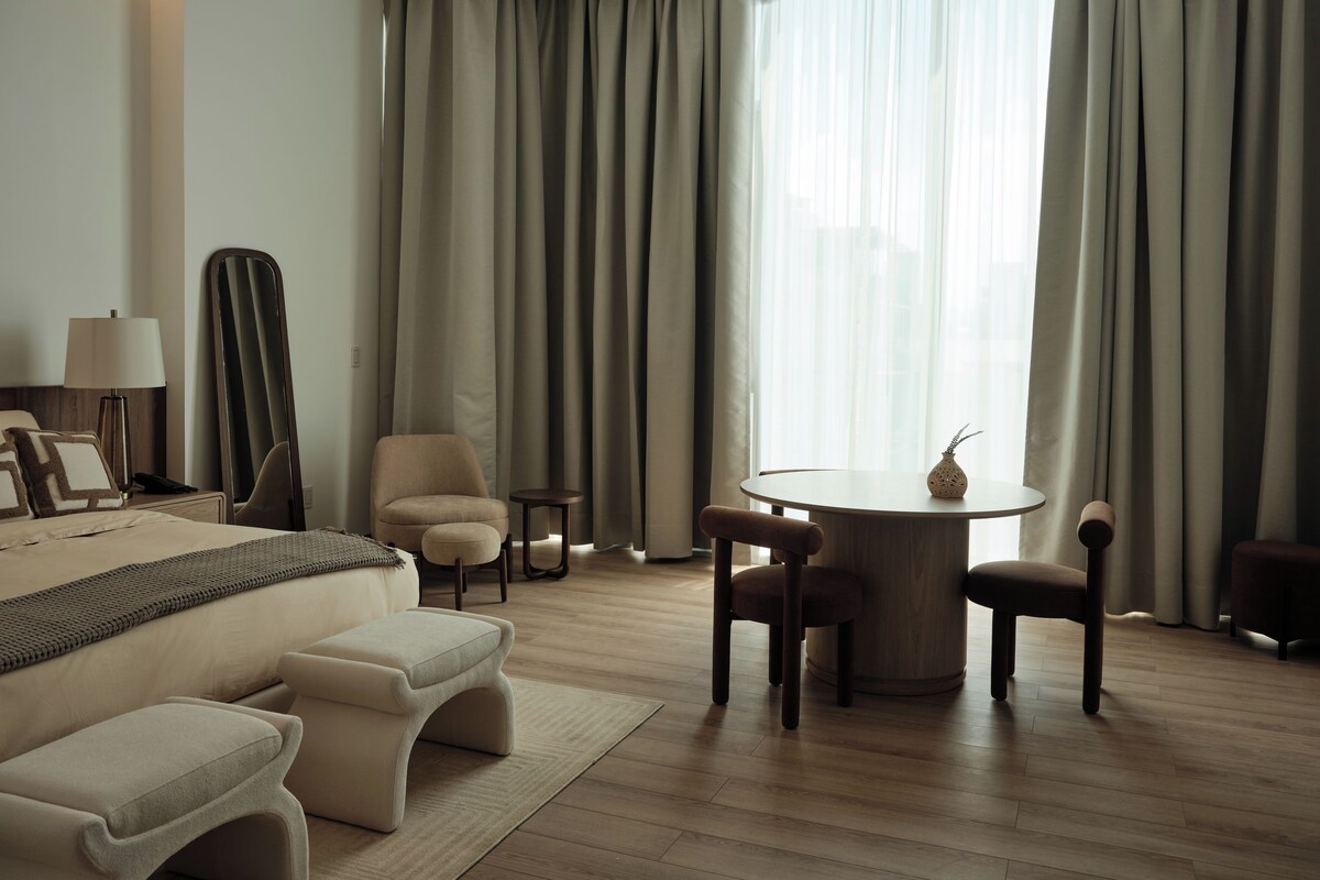 Ein Hotelzimmer mit Bett, Stuhl, Tisch und Deckenventilator.