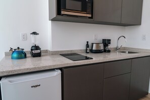 Eine moderne Küche mit integriertem Mikrowellenherd, einer Kaffeemaschine, einem Mixer und einem Geschirrspüler.