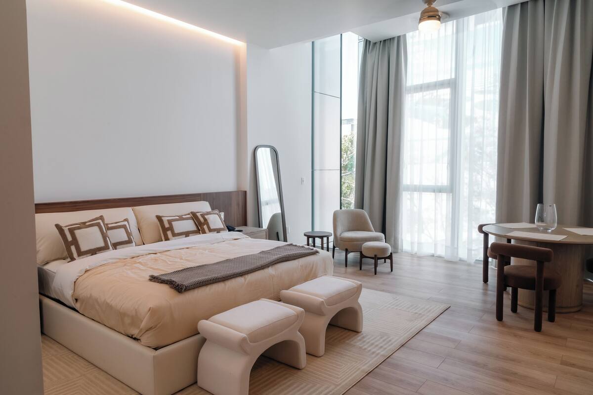 A modern hotel room with a large bed, a desk, and a chair.