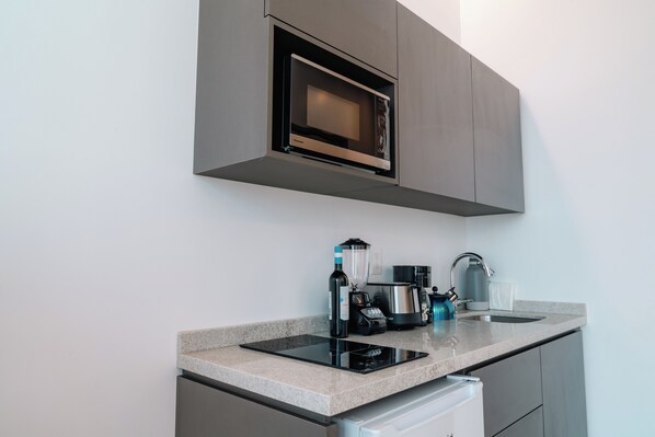A modern kitchen with a built-in microwave, a coffee maker, a kettle, and a blender on the countertop. - Roma Residence Luxury Suites  (Ciudad de México)