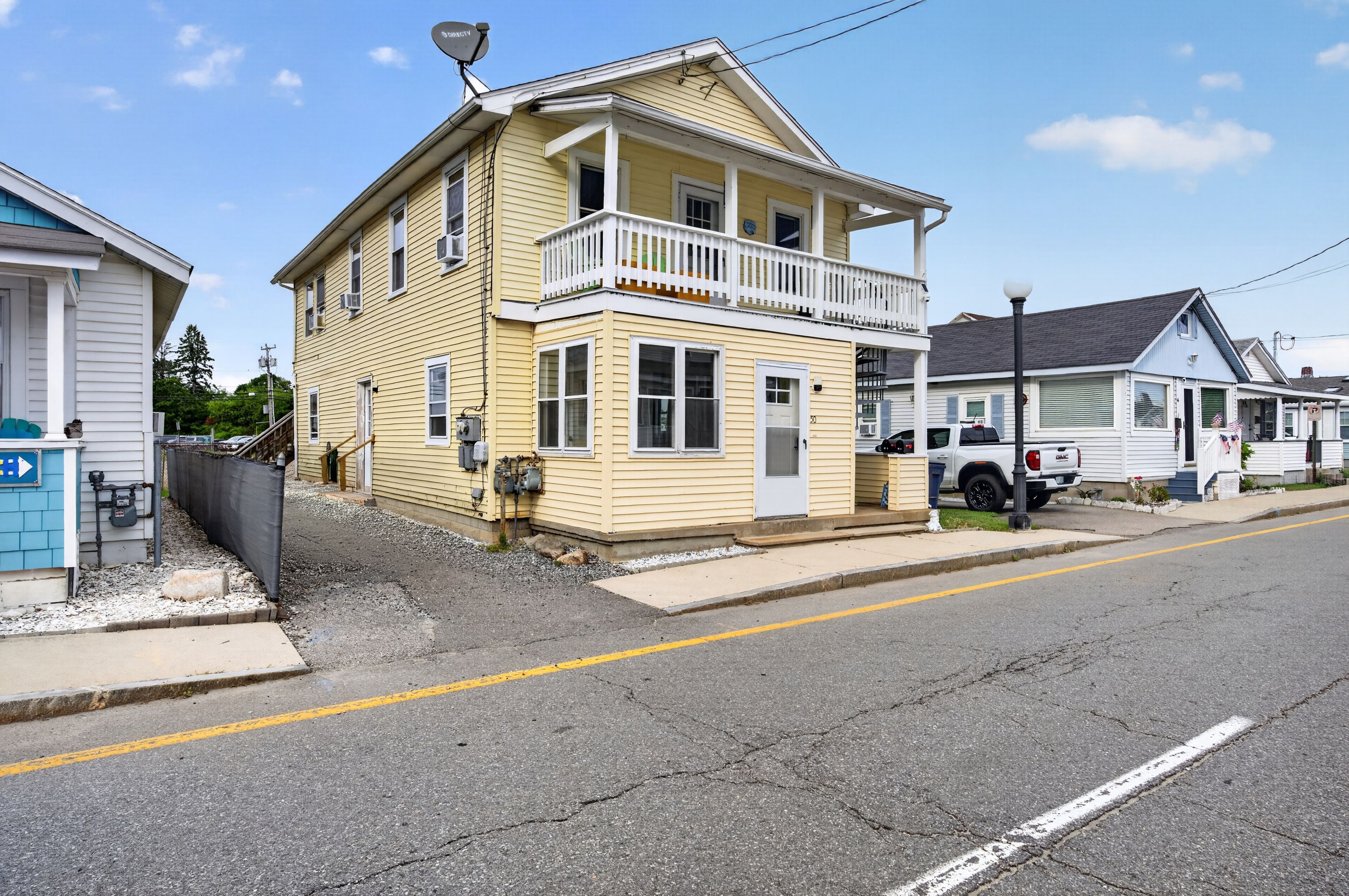 A two-story yellow building with a balcony, a garage, and a street view.