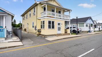 A two-story yellow building with a balcony, a garage, and a street view.