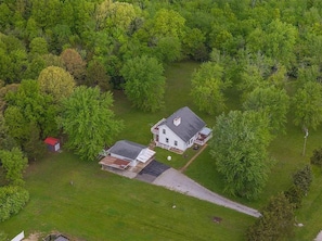 An aerial view of a house surrounded by dense green trees.