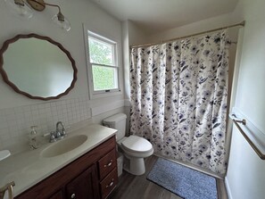 A bathroom with a white sink, vanity, toilet, and shower curtain.