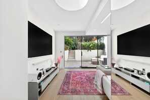 Ein modernes Wohnzimmer mit Fernseher, großem Teppich und einer Schiebetür zu einem Außenbereich.