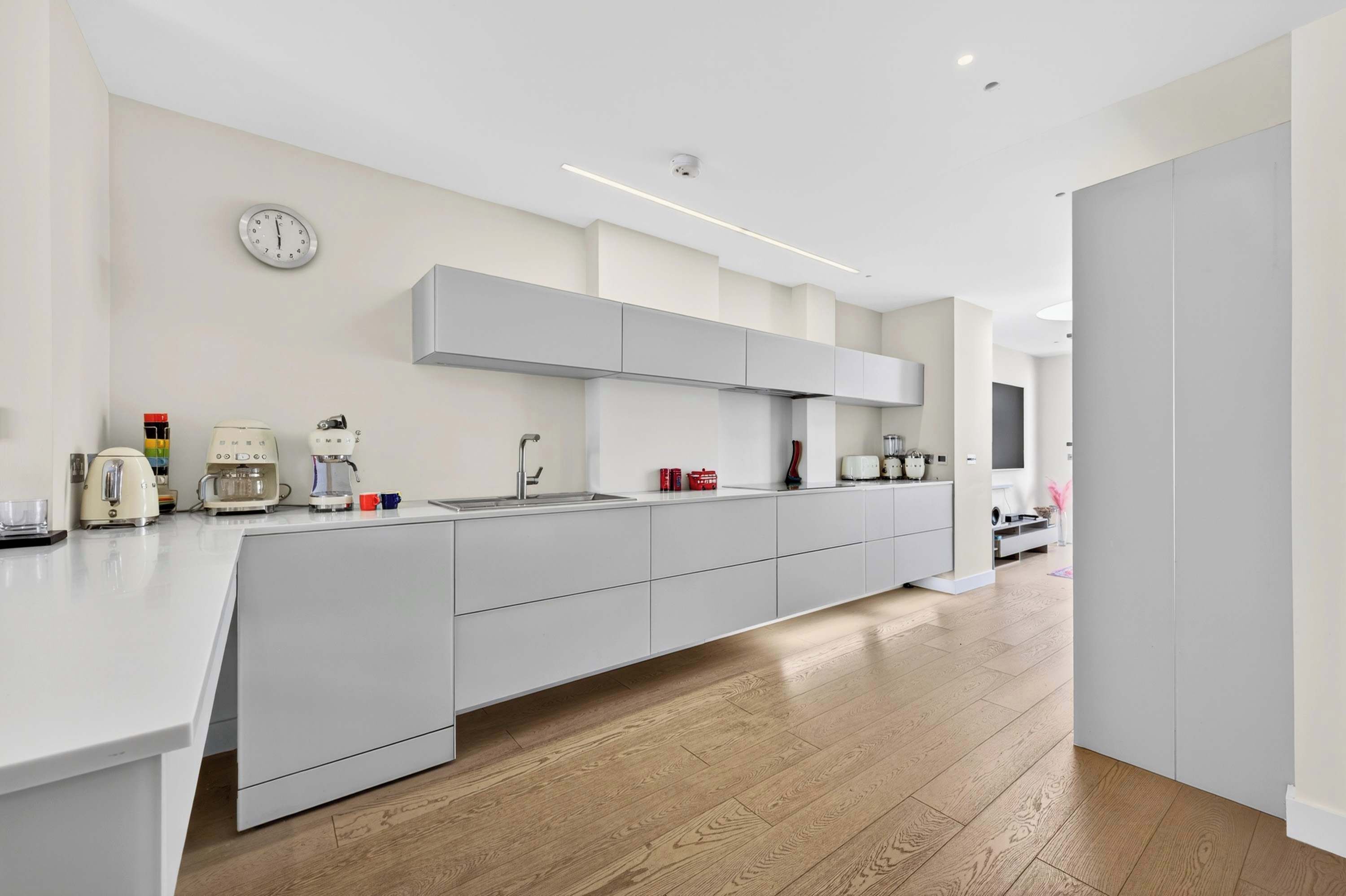 A modern kitchen with a central island, built-in appliances, and a clock on the wall.