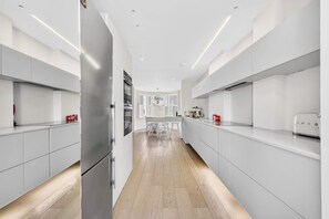 Eine moderne Küche mit weißen Schränken, einer zentralen Kochinsel und einem Edelstahlkühlschrank.