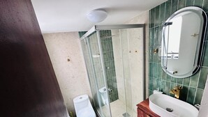 A bathroom with a glass shower enclosure, a toilet, a sink, and a mirror. - Medellín 210  (Ciudad de México)
