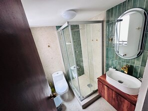 Ein Badezimmer mit Duschkabine aus Glas, Toilette, Waschbecken und Spiegel.