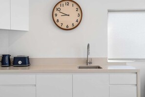 Eine Küche mit Wanduhr, Toaster und Spüle.