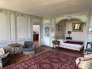Une pièce comprenant un lit, une chaise, une petite table et un tapis à motifs.