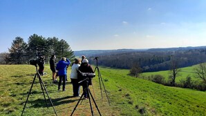 A grassy hill with a camera on a tripod, a group of people, and a forested valley in the distance. - Heritage and nature in the heart of Nièvre (Billy-Chevannes)