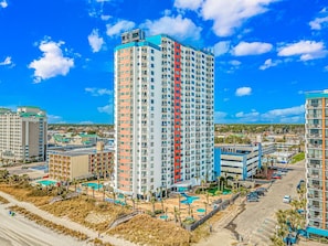Ein Hochhaus-Hotel mit mehreren Stockwerken, einem Schwimmbad und einem Strandbereich.