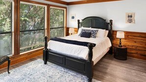 Ein Schlafzimmer mit einem großen Bett, einem Deckenventilator und einem Fenster mit Jalousien.