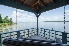 A covered deck with a view of a calm lake and distant shoreline. - Lily Pad Lake House @ Lake Fork (Yantis)