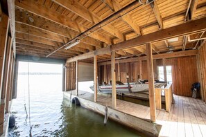 A wooden boat house with a dock extending into a body of water. - Lily Pad Lake House @ Lake Fork (Yantis)