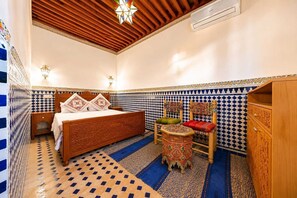 A room with a bed, a chair, a small table, and a cabinet. - Riad AL HANA (Fes)