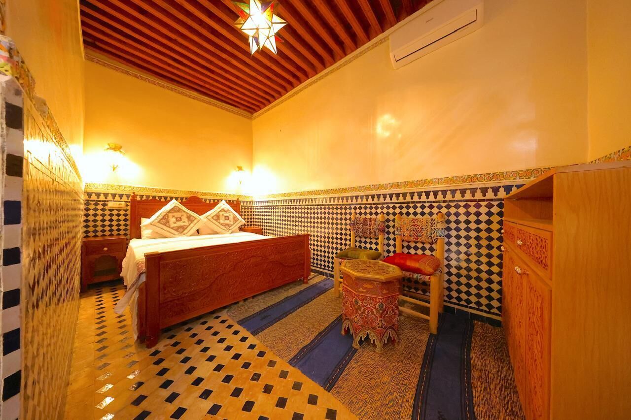 A room with a bed, a nightstand, a small stool, a cabinet, and a star-shaped light fixture.