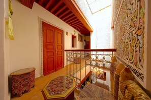 Ein traditionelles Interieur mit einer Holztür, einem Balkon mit schmiedeeisernen Geländern und einer Wandverkleidung.