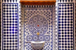 A tiled wall with a geometric pattern and a central circular design. - Riad AL HANA (Fes)