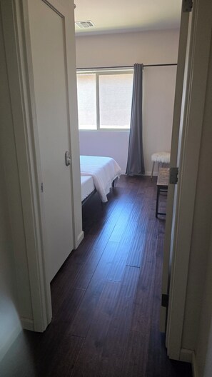 Ein Zimmer mit Bett, Stuhl, Fenster und Tür.