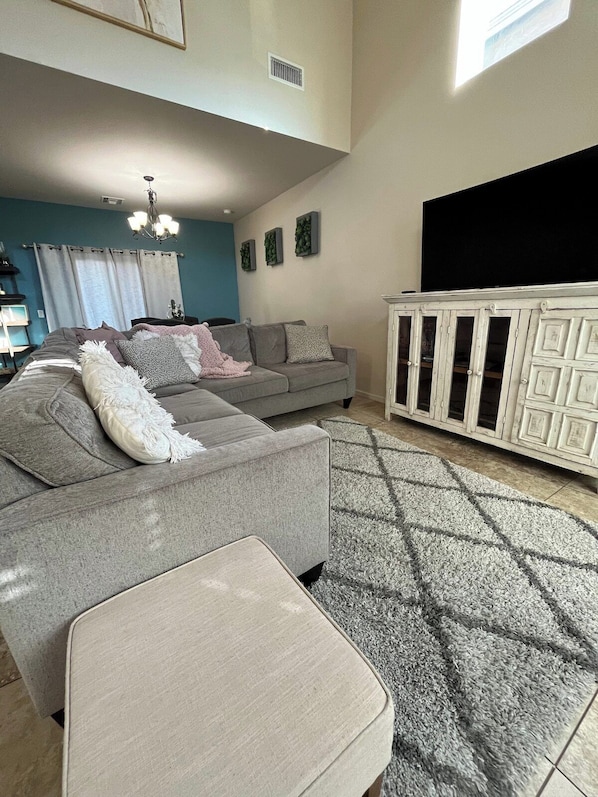 Un salon avec un canapé gris, un meuble blanc et un tapis à motifs.