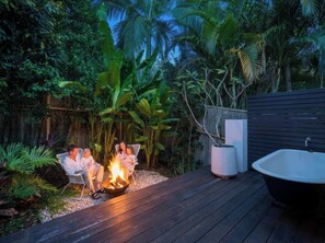 A deck with a fire pit, a bathtub, and lush tropical vegetation. - The Beachside House with Pool & Walk to Beach (Burleigh Heads)