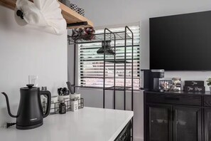 Eine moderne Küche mit Wasserkocher, Besteckhalter und einem Fernseher.