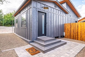 Ein modernes Haus mit grauem Anstrich, einer dunklen Haustür und einem Holzzaun.
