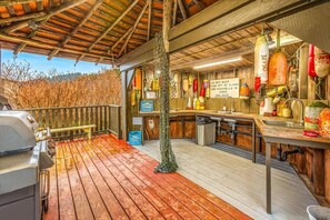 Cocina al aire libre techada con una parrilla, un lavamanos y diversos utensilios de cocina.