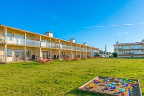 A hotel with multiple balconies, a grassy lawn, and outdoor seating.