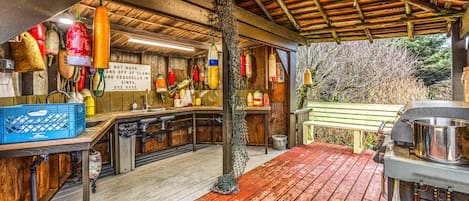 Una cocina rústica con vigas de madera, una terraza de madera y varios objetos colgantes.