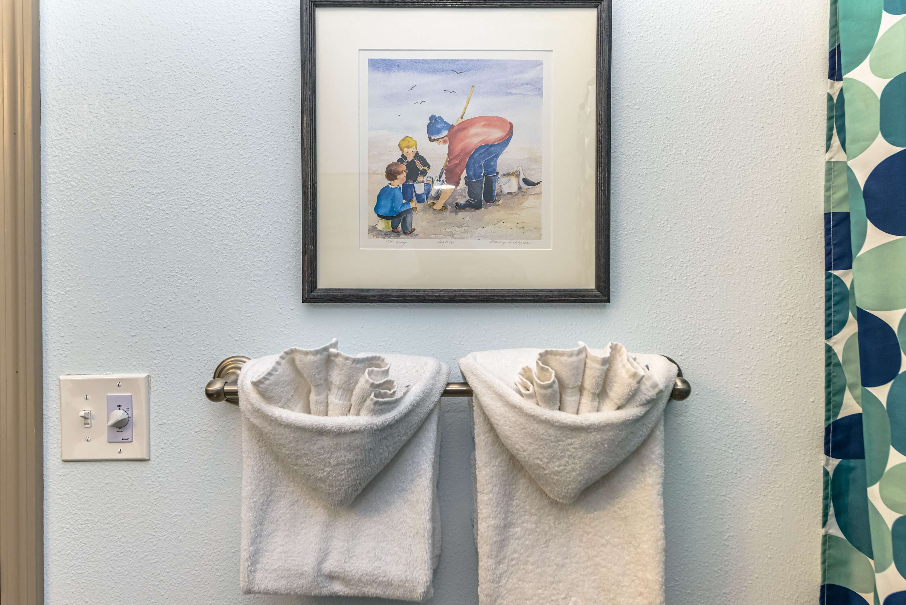 A framed artwork above a towel rack with two towels.