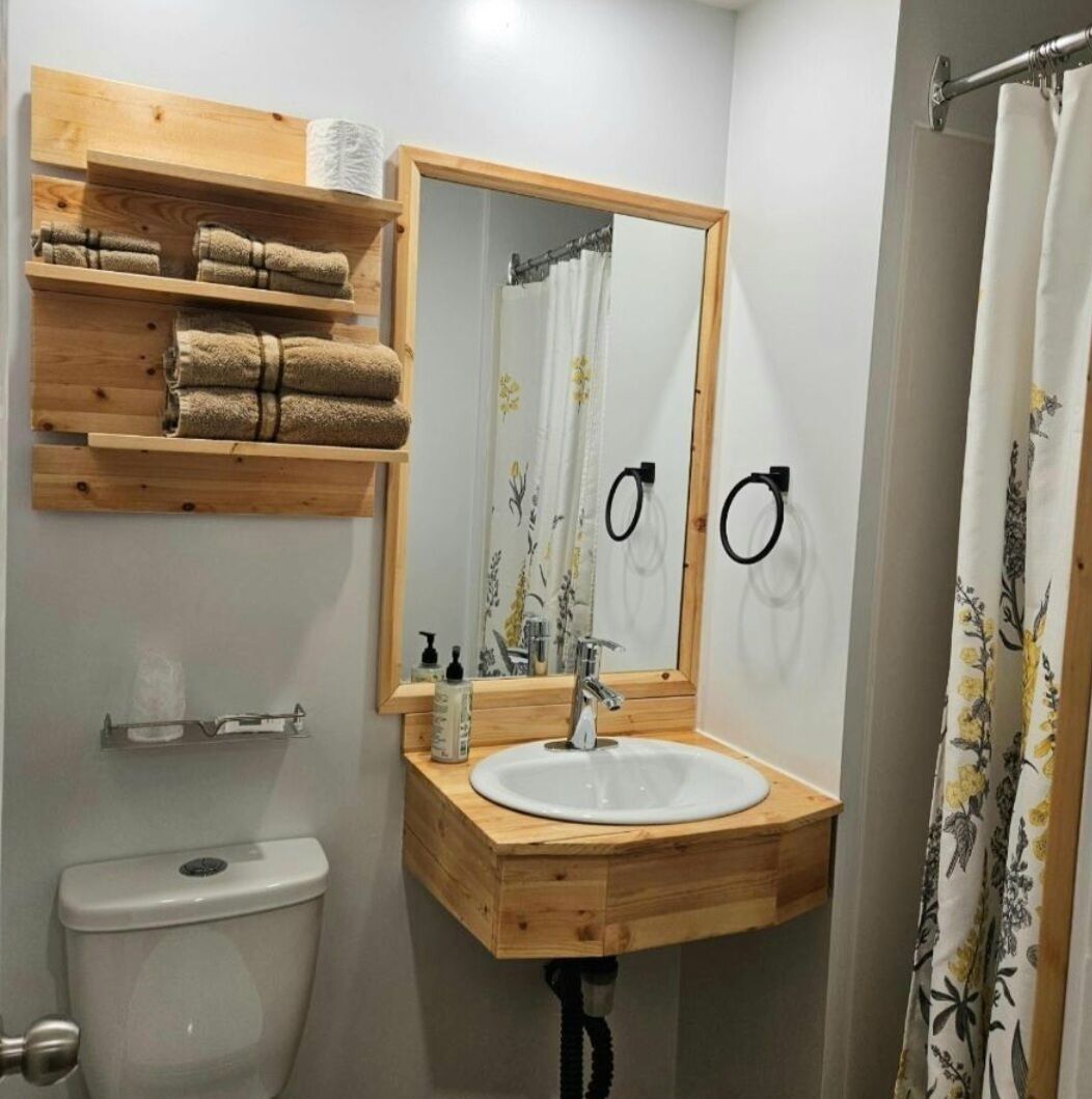 A bathroom with a wooden vanity, a sink, a toilet, and a shower curtain.