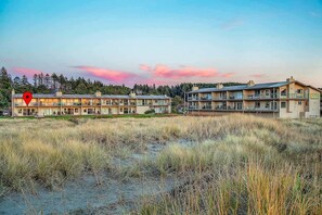 A hotel with multiple buildings, a grassy area in front, and a forest in the background.
