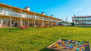 Ein mehrstöckiges Hotel mit einem begrünten Innenhof, Außenbestuhlung und einem Poolbereich.