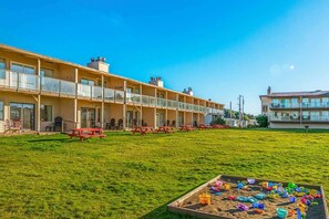 A multi-story hotel with a grassy courtyard, outdoor seating, and a pool area.