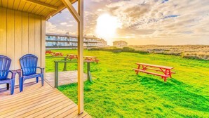 Ein überdachter Außenbereich mit Picknicktischen und -stühlen, eine Rasenfläche und Gebäude im Hintergrund.