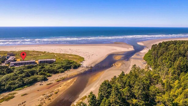 Un paysage côtier comprenant une plage, une zone boisée et un ensemble de bâtiments comprenant plusieurs structures.